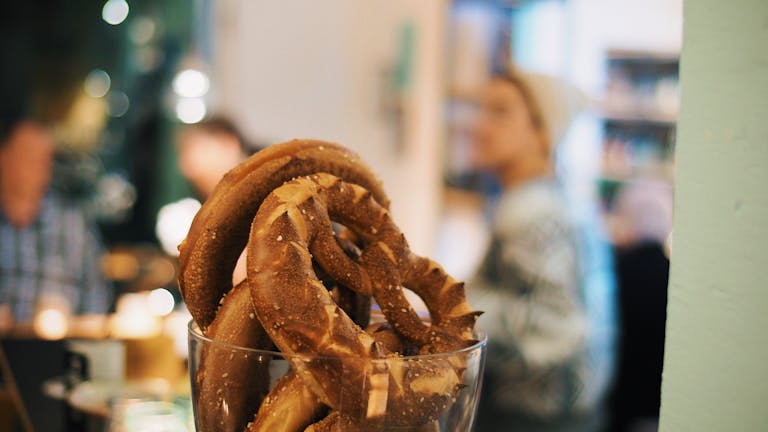 Appetizing pretzels in a glass jar, captured in a cozy café atmosphere.