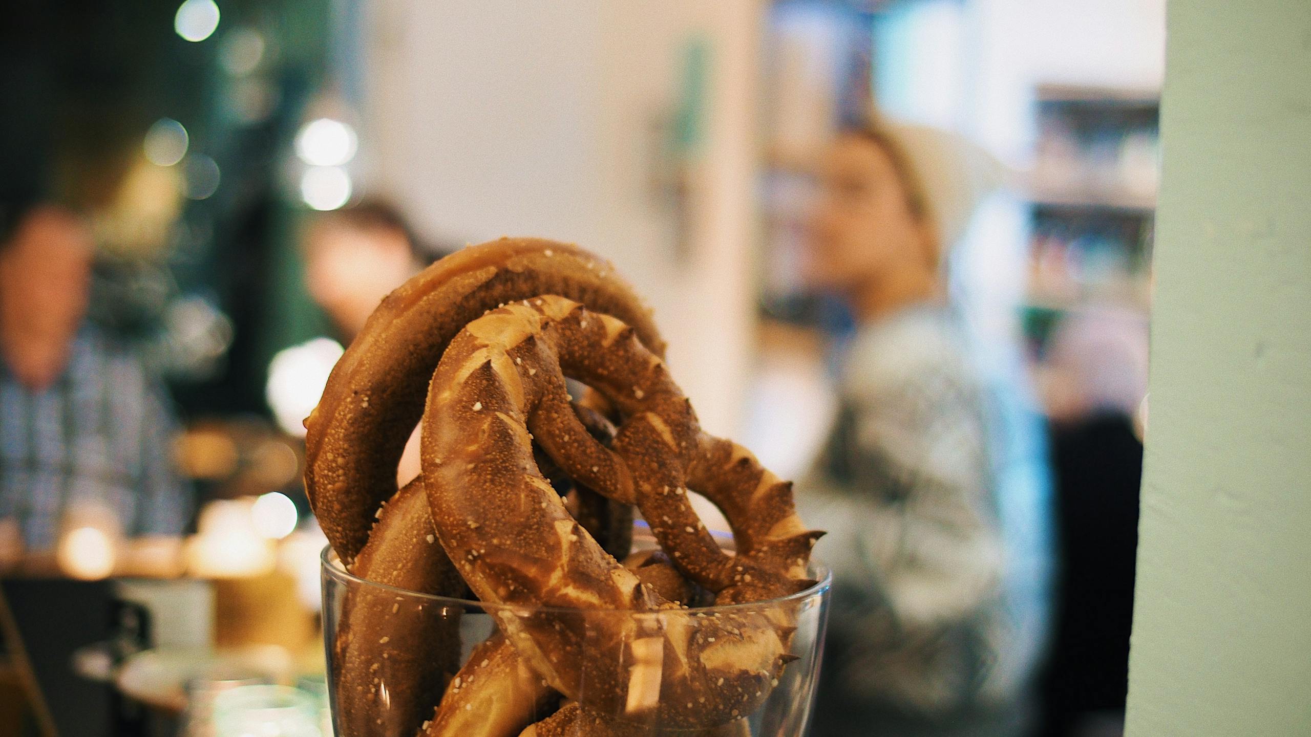 Appetizing pretzels in a glass jar, captured in a cozy café atmosphere.
