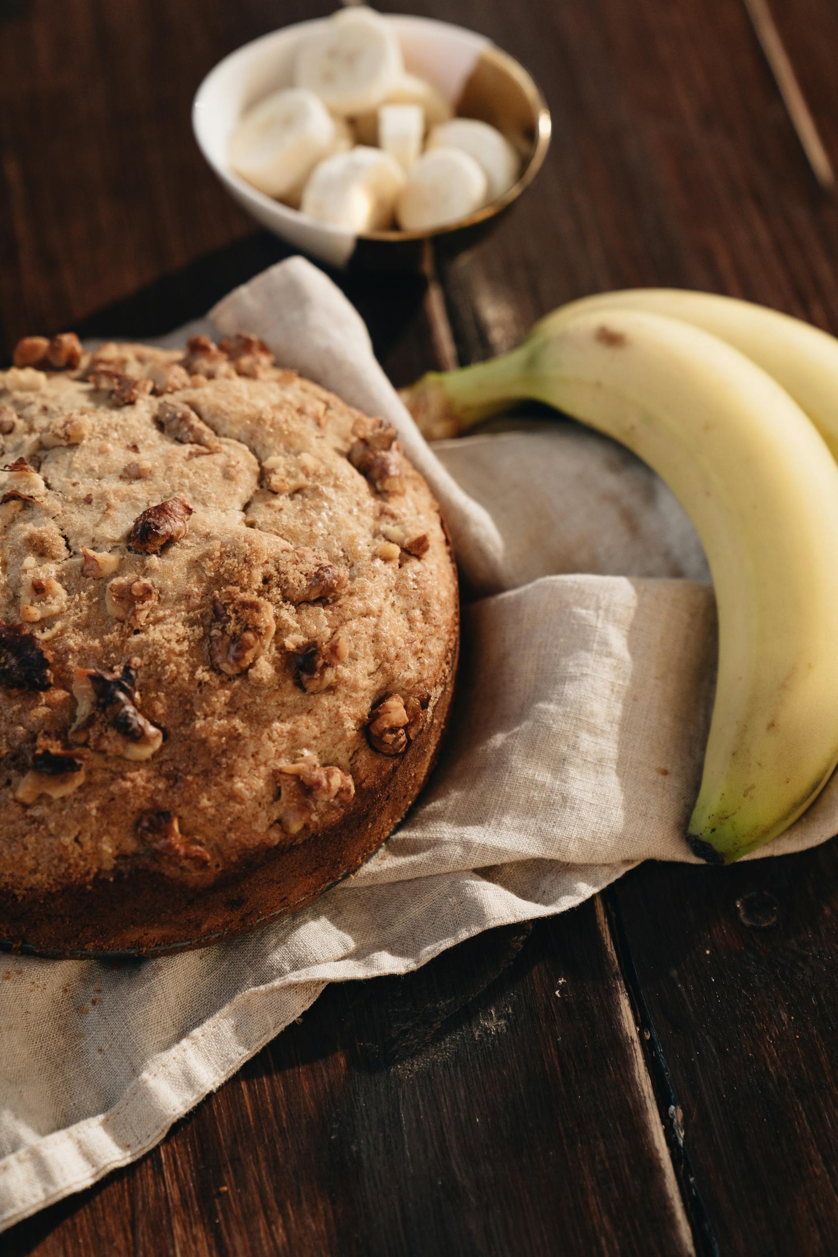 A delicious loaf of banana walnut bread paired with fresh bananas on a wooden table.