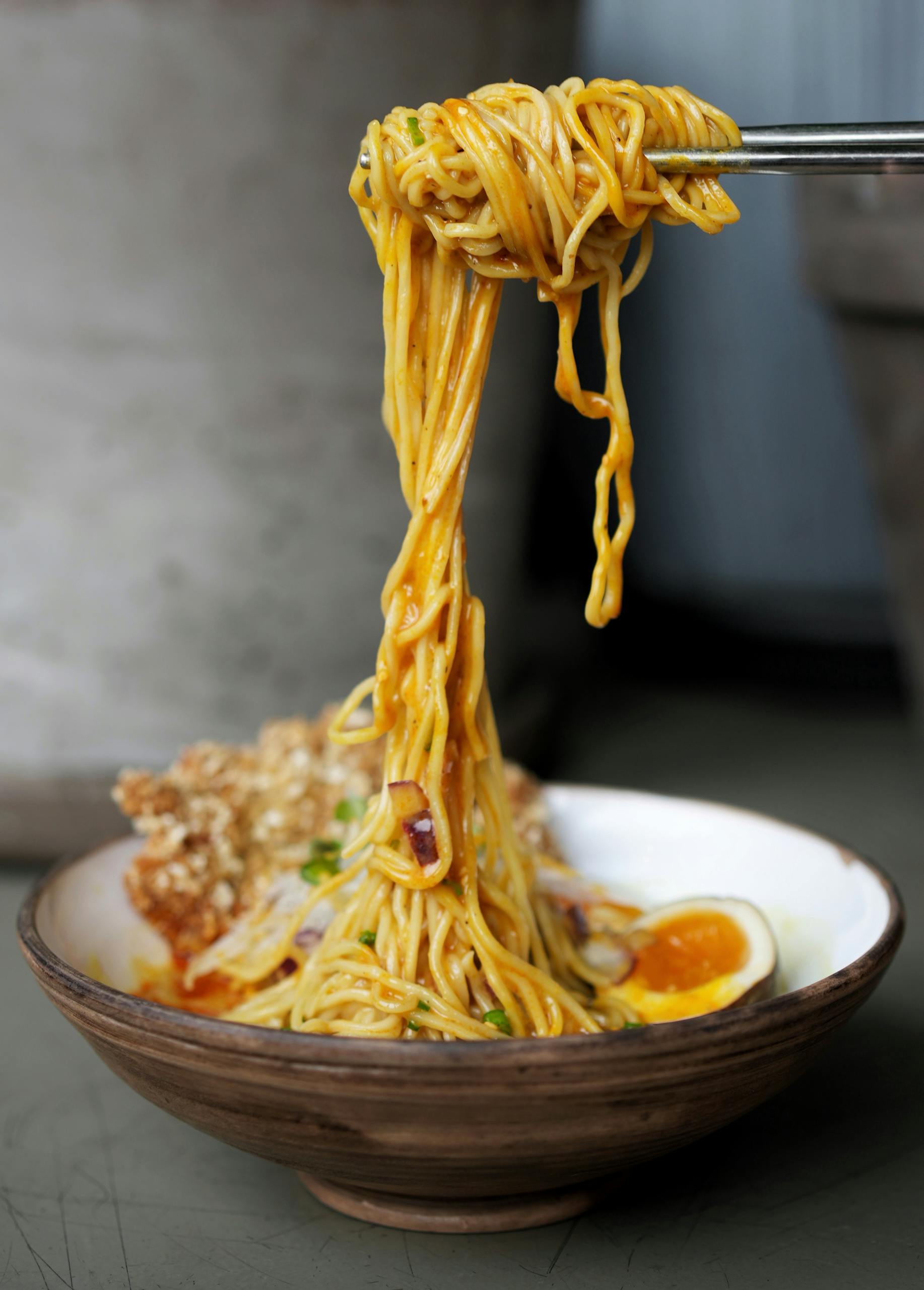 Close-up of savory ramen noodles in a bowl with egg and greens.