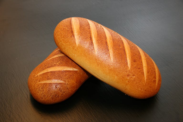 Close-up of two freshly baked loaves with crispy crust, ideal for food and still life photography.
